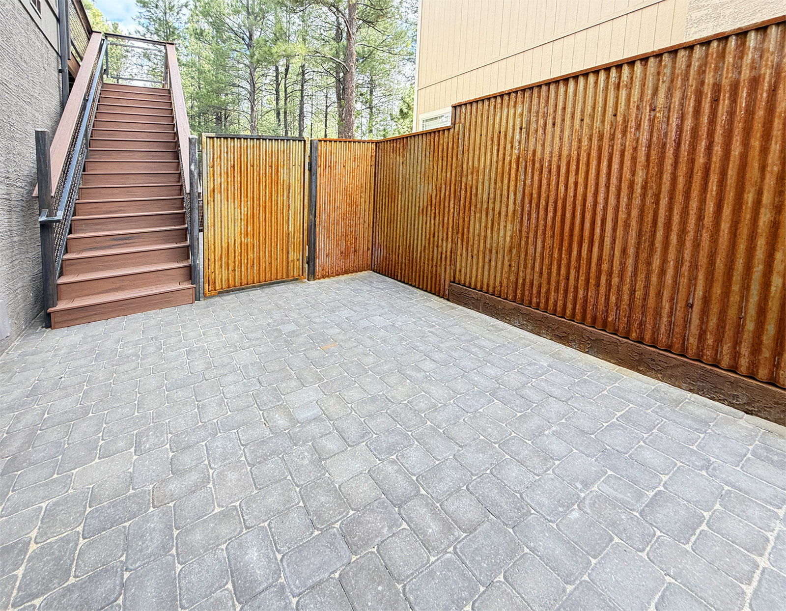Highwood Construction designed this custom courtyard that includes new pavers and a rusted metal fence.  Also pictured is a Trex composite staircase.  Location is Ponderosa Trails neighborhood in Flagstaff Arizona.