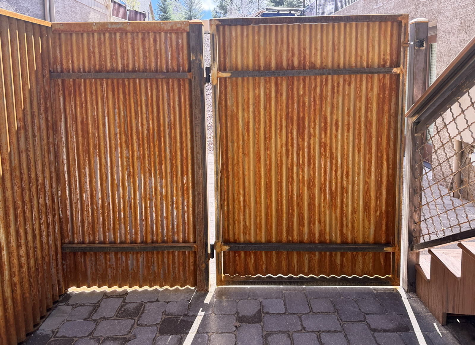 A corrugated rusting metal fence and gate installed in Flagstaff AZ